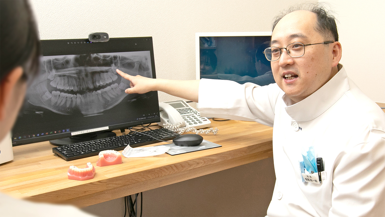 モニターを使って治療計画や費用について説明する院長